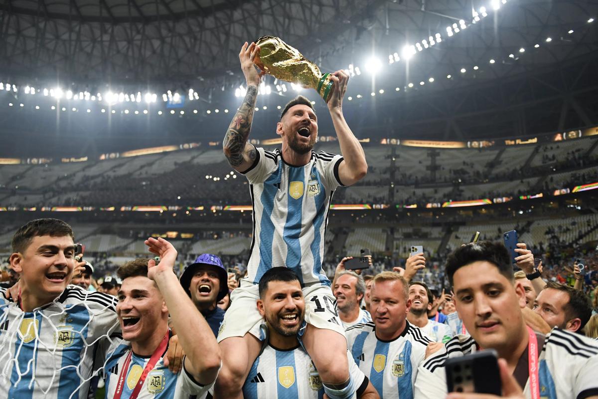 卡塔爾盧賽爾城 - 12 月 18 日：阿根廷隊(duì)的萊昂內(nèi)爾·梅西 (Lionel Messi) 在國際足聯(lián)世界杯期間取得勝利后，在塞爾吉奧·“昆”·阿奎羅的肩上慶祝 2022 年卡塔爾世界杯冠軍獎(jiǎng)杯